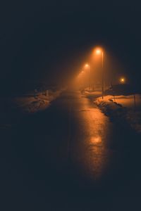 Illuminated street lights against sky at night during winter