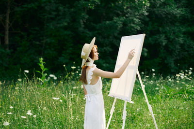 Side view of woman holding umbrella standing on field