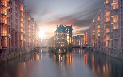 Reflection of buildings in city at sunset