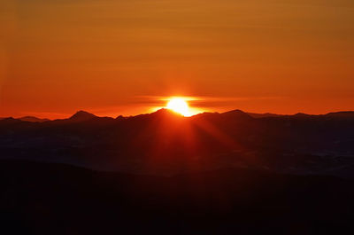 Scenic view of silhouette mountains against orange sky