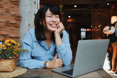 Young woman using phone while sitting on table