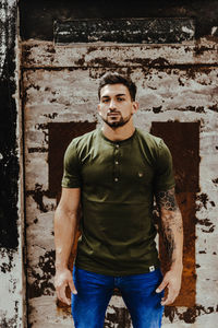 Portrait of young man standing against wall