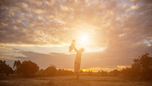 People standing on field against sky during sunset