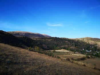 Scenic view of landscape and mountains against blue sky