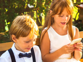 Cute girl using smart phone sitting outdoors