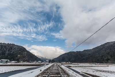 Road by mountains against sky