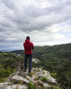 Rear view of man standing on mountain against sky