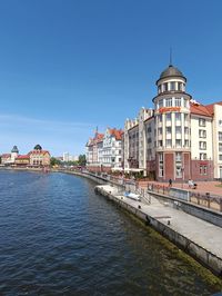 Buildings by river against sky