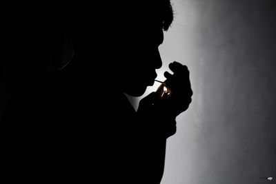 Side view of young man smoking at home