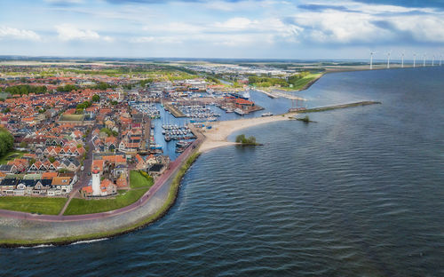 Aerial view of city by sea against sky