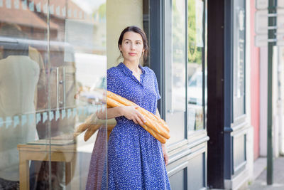 Young woman buying a french baguette