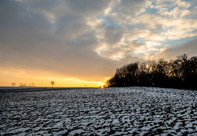 Scenic view of snow covered field against sky during sunset