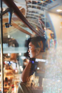 Close-up of woman looking through glass window