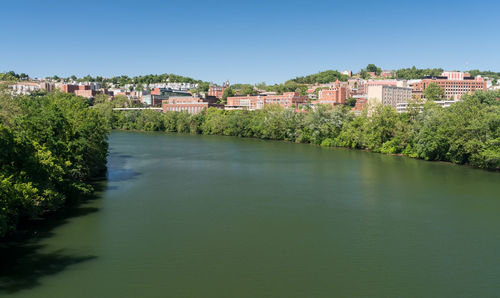 River amidst buildings against clear blue sky