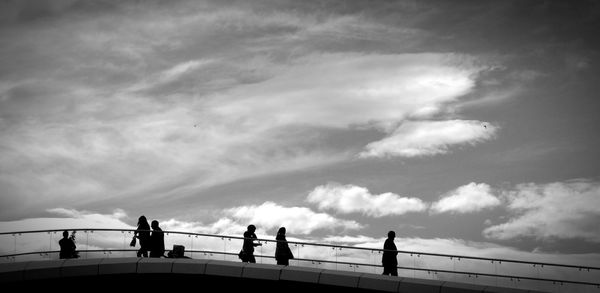 Low angle view of silhouette people walking on bridge