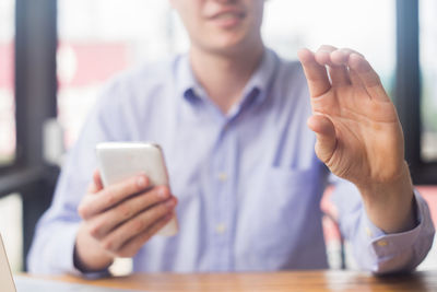 Midsection of man using mobile phone while gesturing
