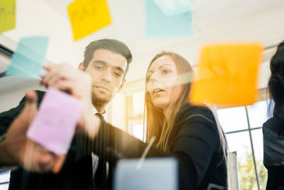 Portrait of businessman with colleague holding adhesive notes in office