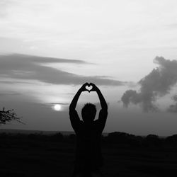 Silhouette man showing heart shaped on field
