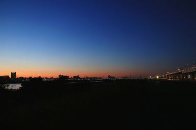 Illuminated cityscape against clear sky at sunset