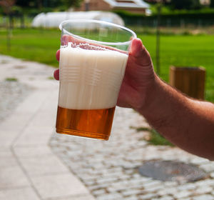 Close-up of hand holding beer glass