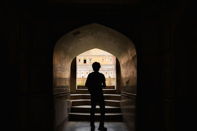 Rear view of silhouette man standing in archway at historic building