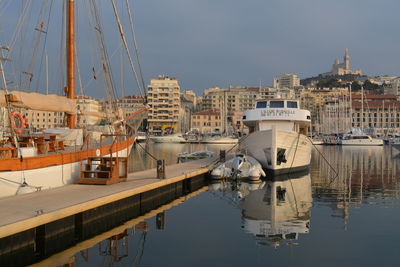 Boats moored at harbor against buildings in city