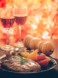 Close-up of food and pepper mill by red wine in glass on table