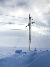 Low angle view of electricity pylon on field against sky