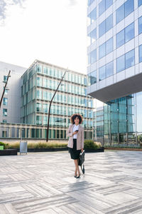 Full length of young woman standing against building