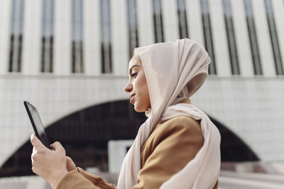 Young businesswoman using tablet pc in front of building