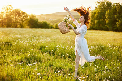 Rear view of woman with arms raised standing on field