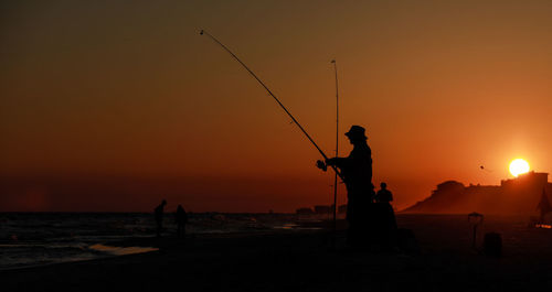Silhouette people fishing at sunset