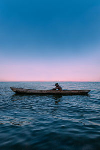 People in boat in sea against clear blue sky