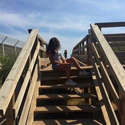 Full length of man sitting on staircase against sky