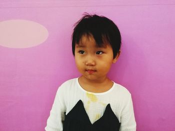 Cute girl standing against pink wall