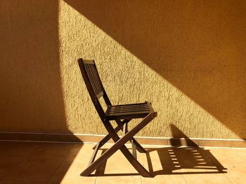 High angle view of empty chair against wall
