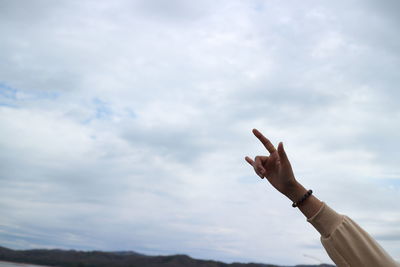 Cropped hand of person gesturing against sky