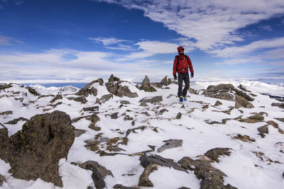 Man walking on snow covered mountain against sky