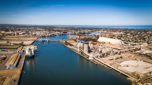 High angle view of townscape by sea against blue sky