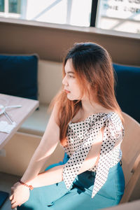 Young woman using laptop while sitting on sofa at home