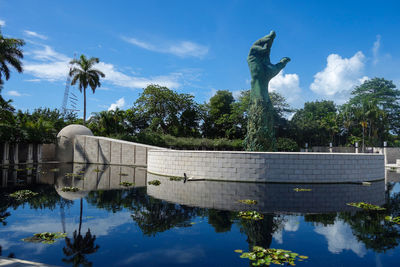 Statue by lake against sky