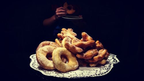 Close-up of fresh sweet food with person against black background