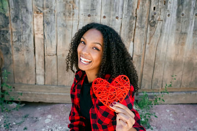 Portrait of smiling young woman holding heart shape