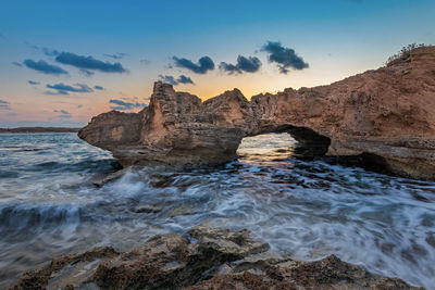 Rock formation on sea against sky during sunset