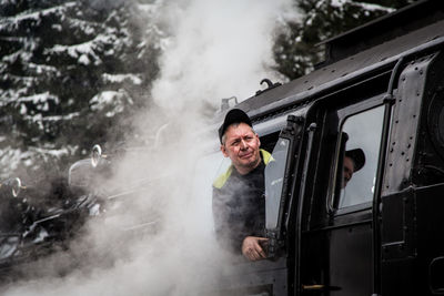 Side view of a smiling man standing on car