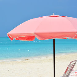 Close-up of deck chairs on beach against clear blue sky