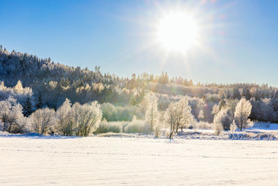 Snow covered field against sky during sunset