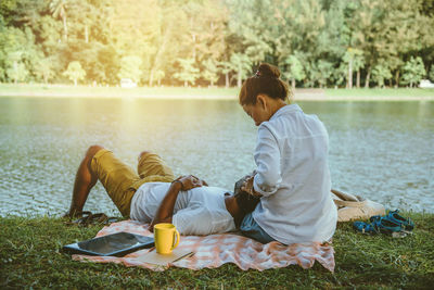 Rear view of friends sitting by lake