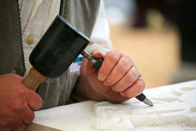 Midsection of man carving at table