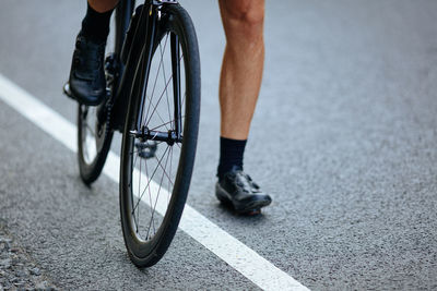 Low section of man riding bicycle on road